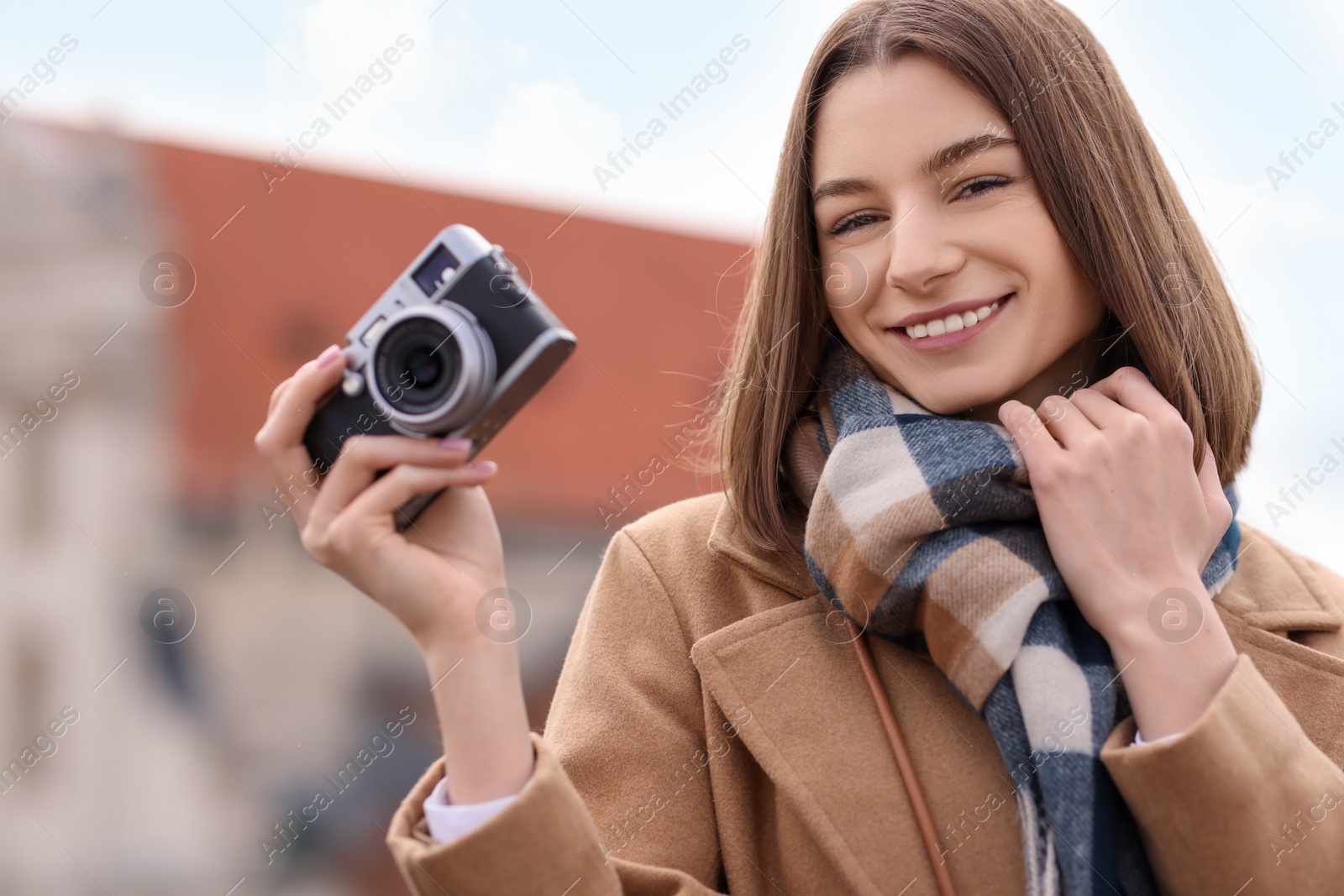 Photo of Beautiful woman in warm scarf with vintage camera outdoors