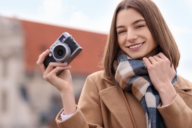 Beautiful woman in warm scarf with vintage camera outdoors