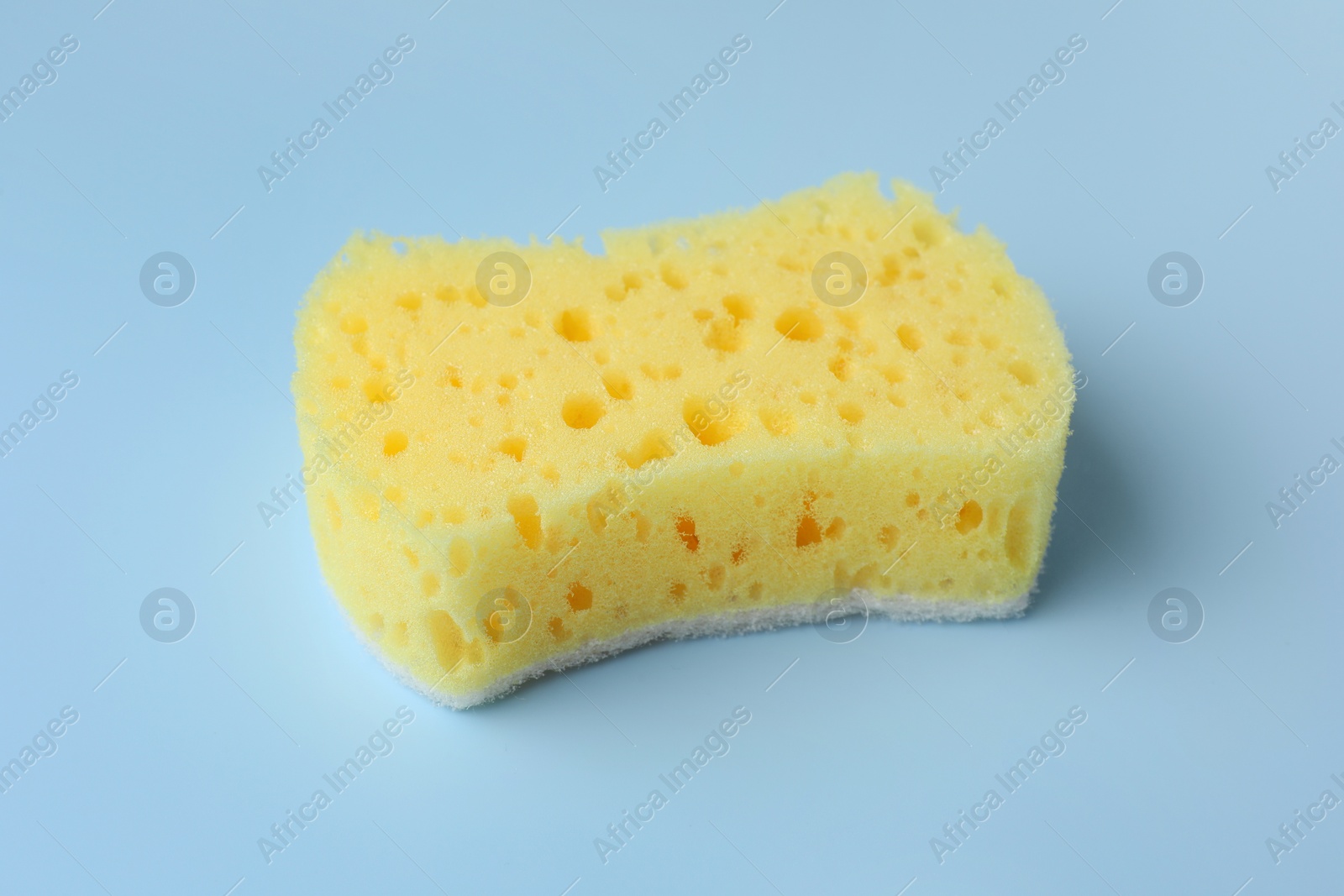Photo of New yellow sponge on light blue background