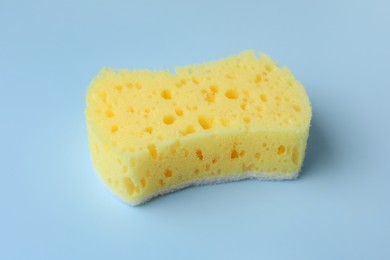 Photo of New yellow sponge on light blue background