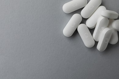 Photo of Pile of calcium supplement pills on grey background, flat lay. Space for text