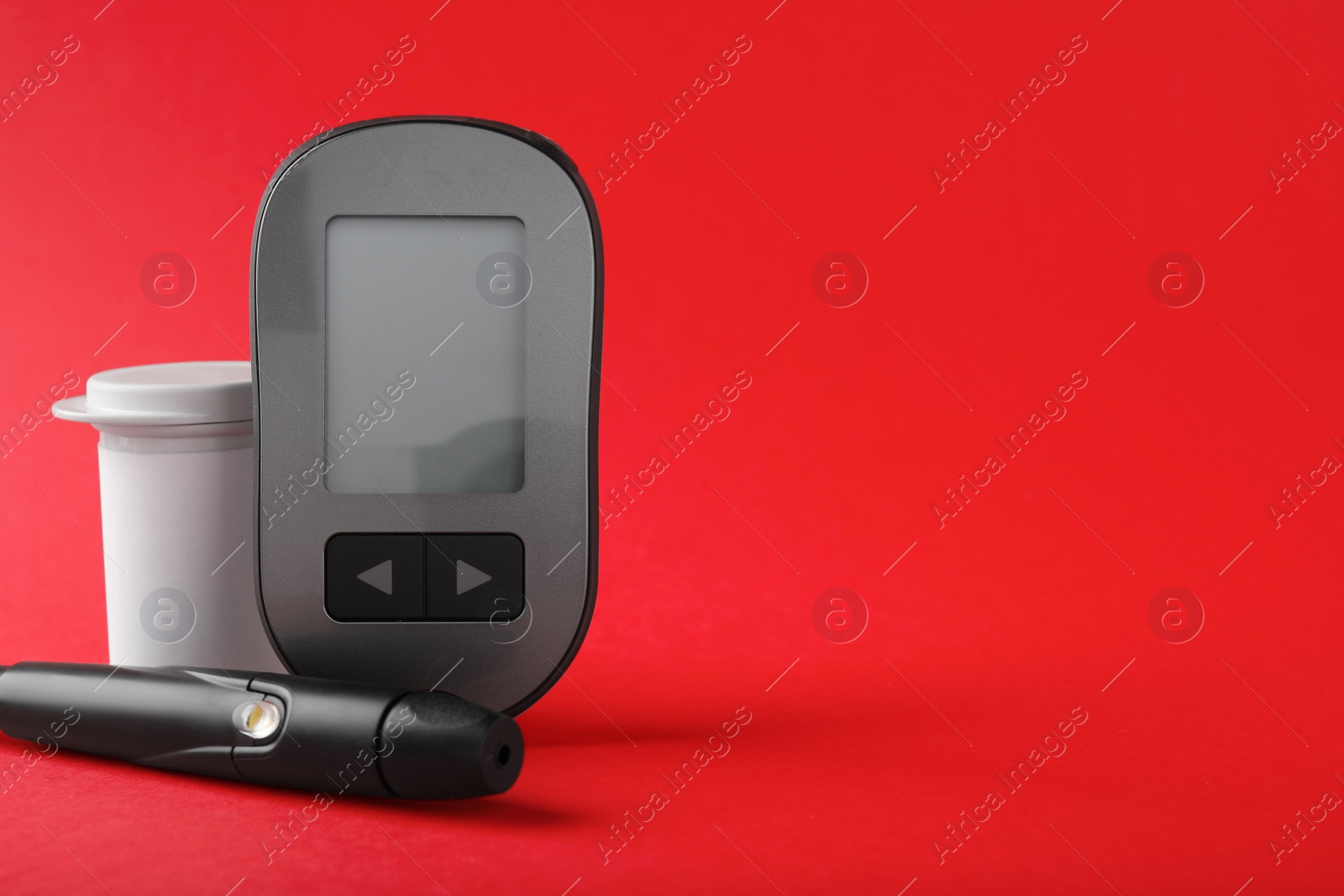 Photo of Digital glucometer, lancet pen and container on red background, space for text. Diabetes control