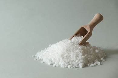 Photo of Organic salt and wooden scoop on light grey background. Space for text