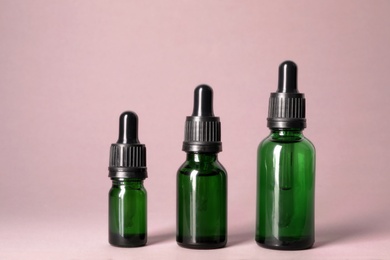 Cosmetic bottles of essential oils on color background