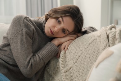 Photo of Sad young woman lying on sofa at home