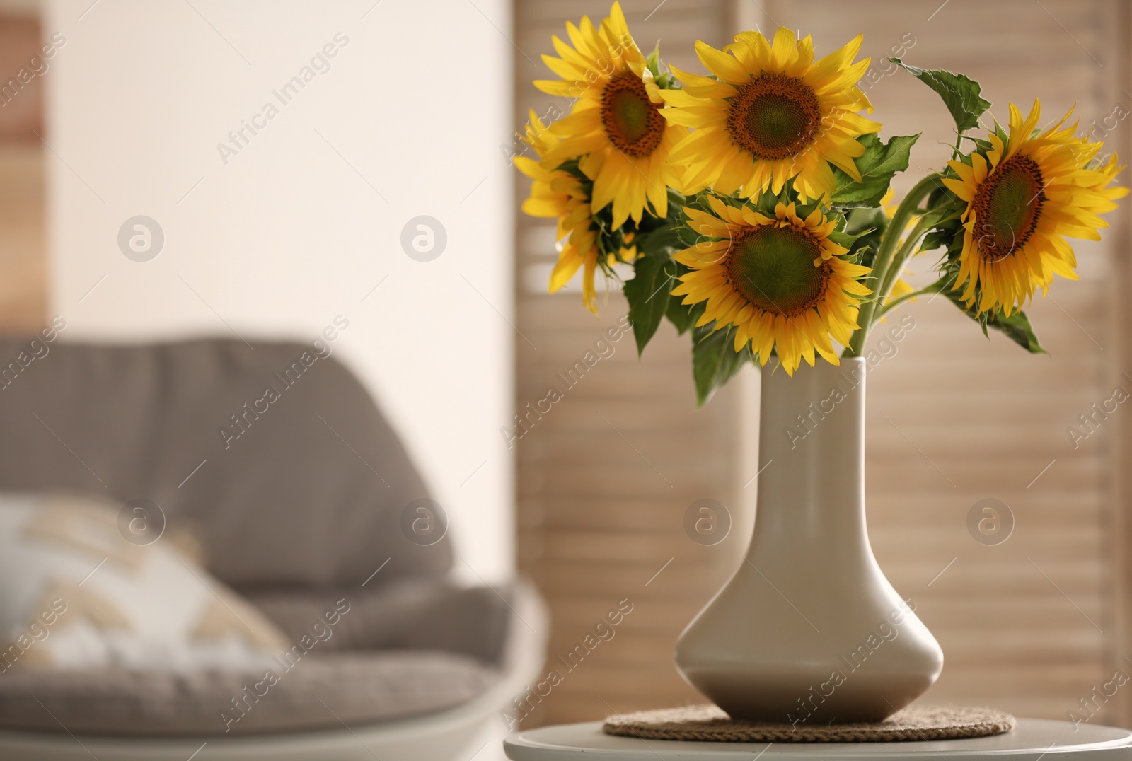 Photo of Vase with beautiful yellow sunflowers on table in room, space for text