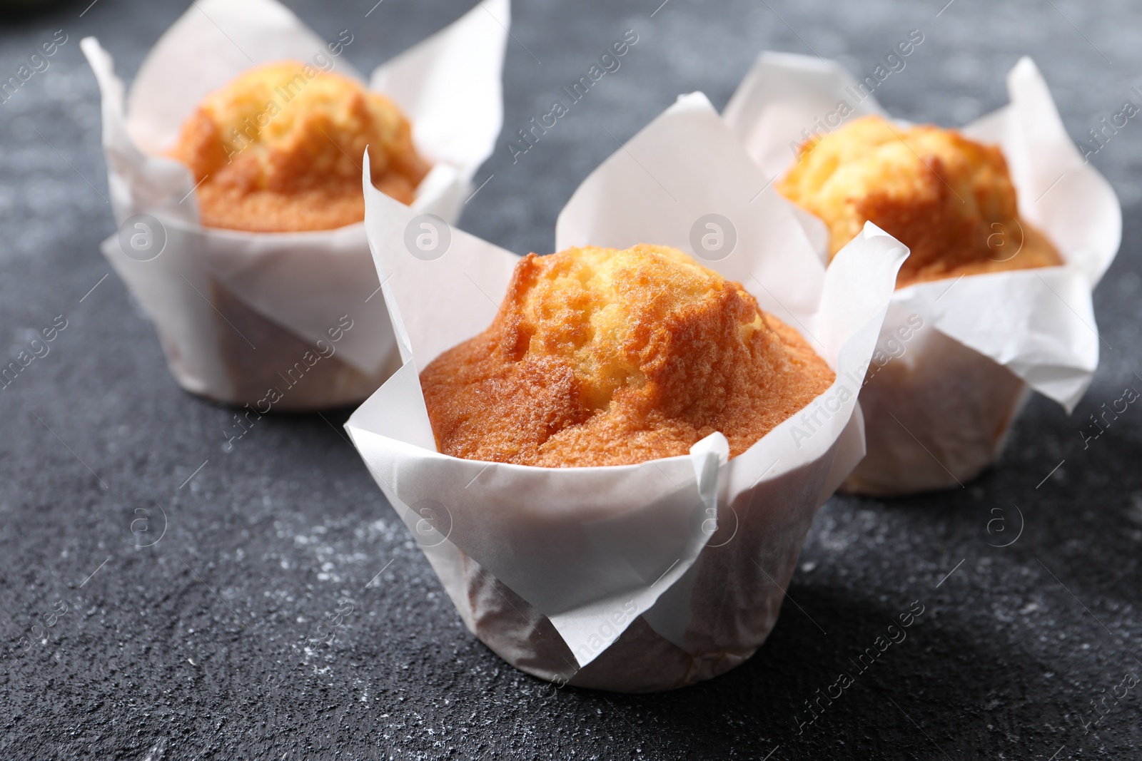 Photo of Delicious sweet muffins on black textured table, closeup