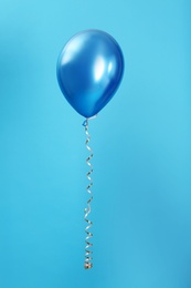 Bright balloon with ribbon on color background