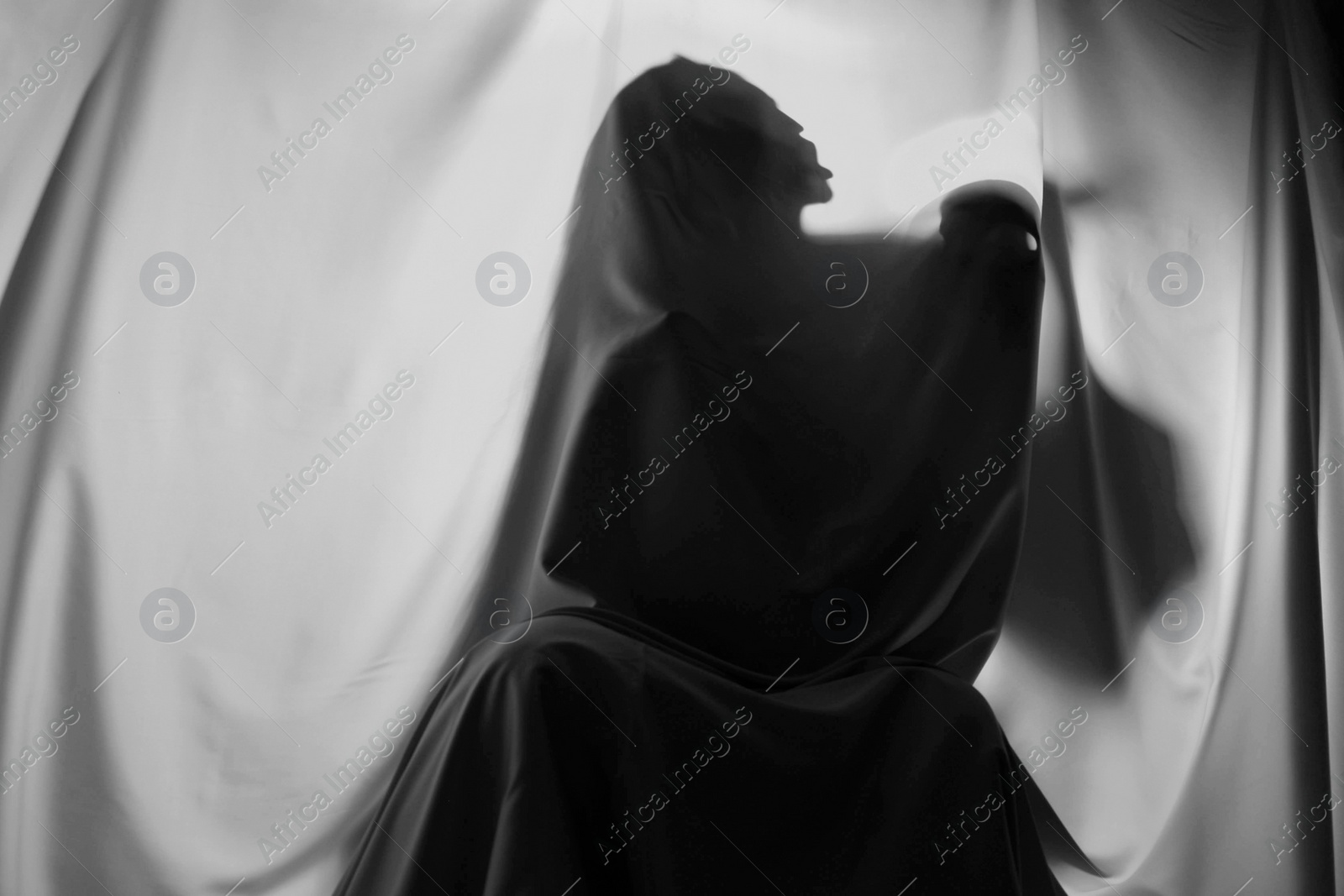 Photo of Silhouette of creepy ghost with skull behind grey cloth, space for text