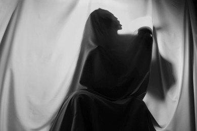 Silhouette of creepy ghost with skull behind grey cloth, space for text