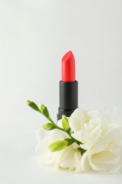 Beautiful lipstick and flowers on white background