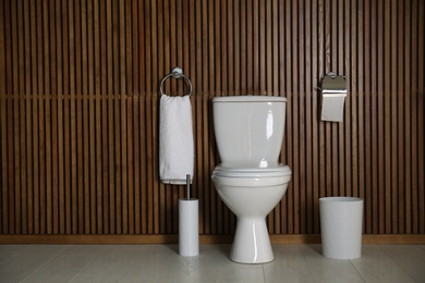 Simple bathroom interior with new toilet bowl near wooden wall. Space for text