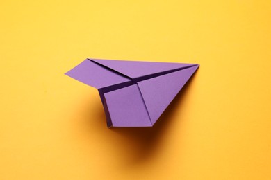 Photo of Handmade purple paper plane on yellow background