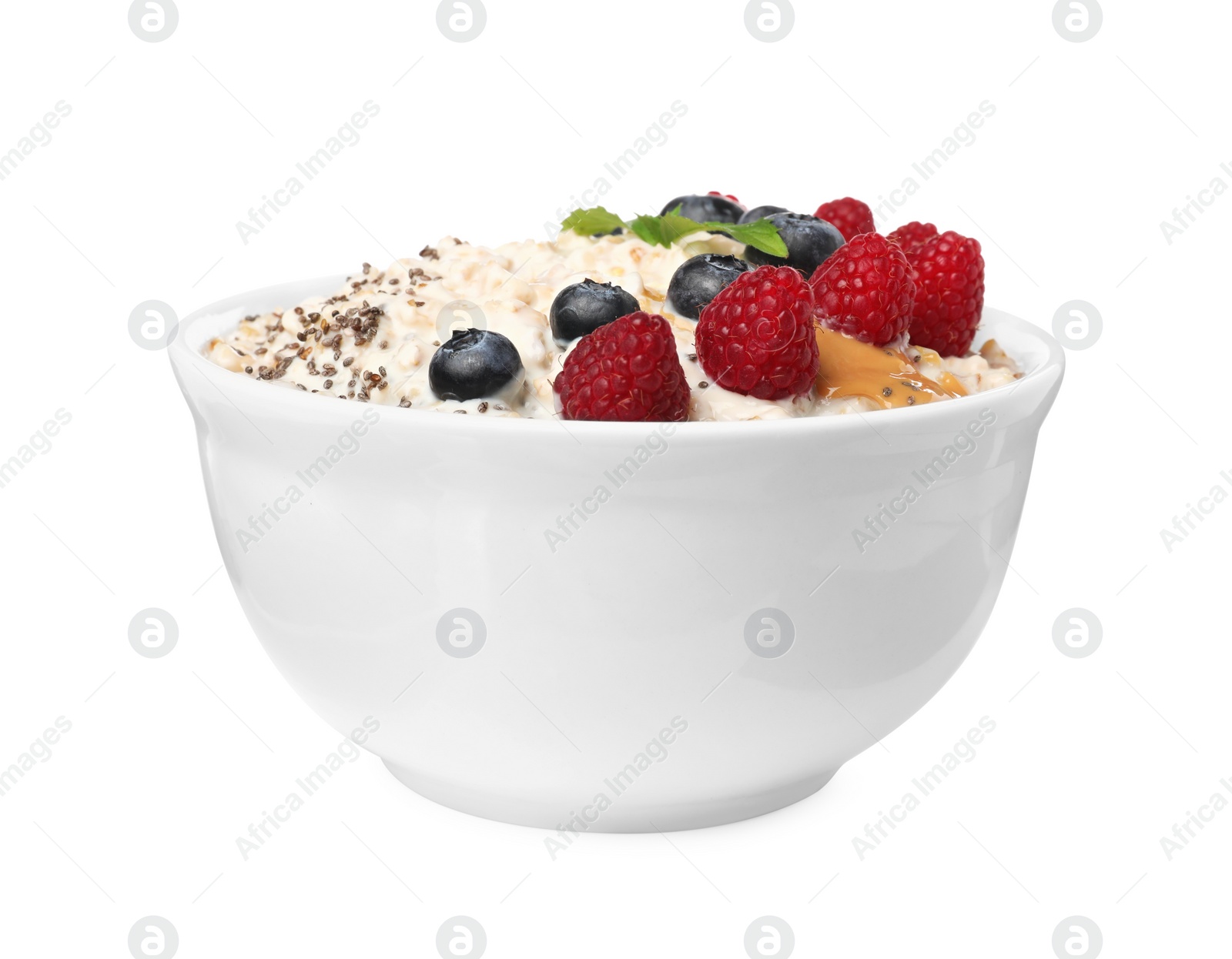 Photo of Tasty boiled oatmeal with berries, chia seeds and peanut butter in bowl isolated on white