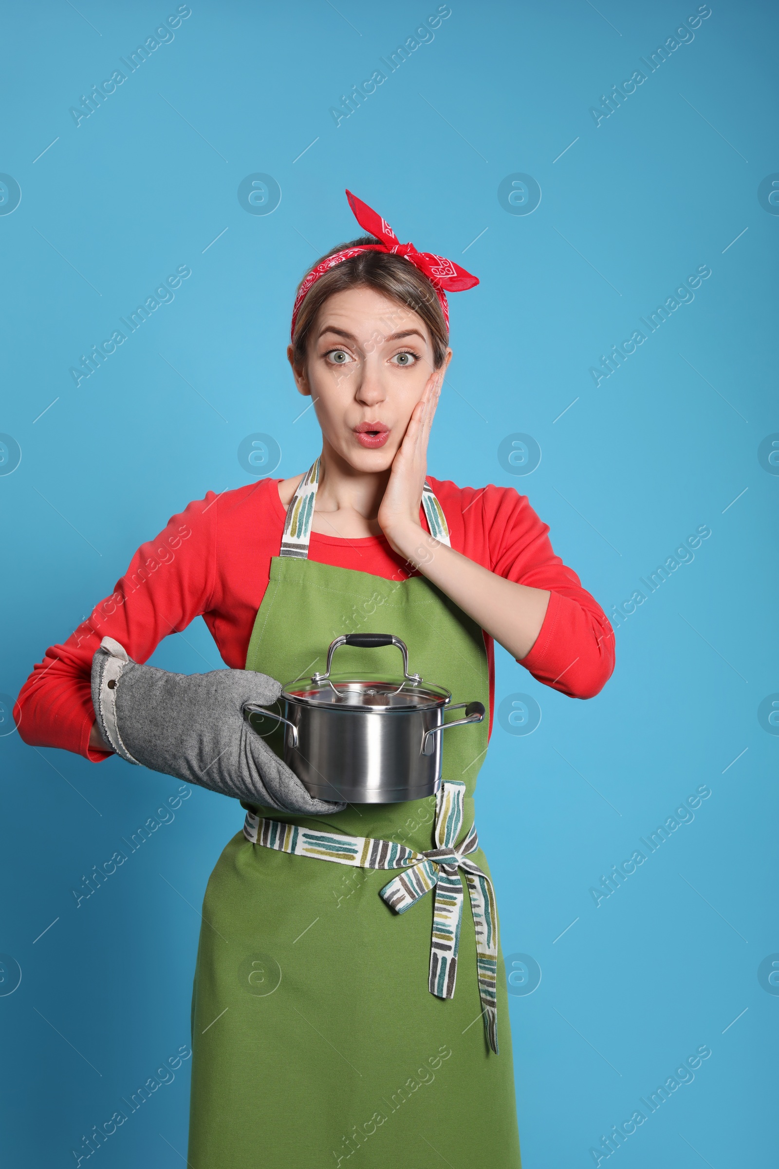 Photo of Young housewife with pot on light blue background