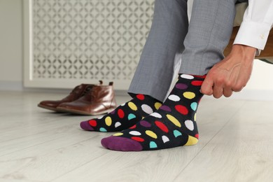 Man putting on colorful socks indoors, closeup