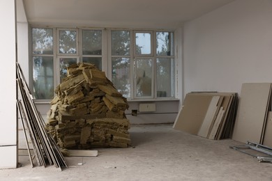 Photo of Used glass wool and different building materials in room prepared for renovation