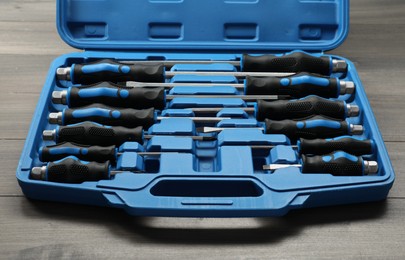 Set of screwdrivers in open toolbox on wooden table, closeup