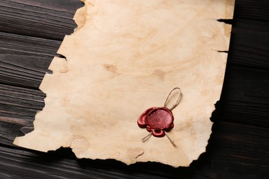 Photo of Sheet of old parchment paper with wax stamp on wooden table. Space for text