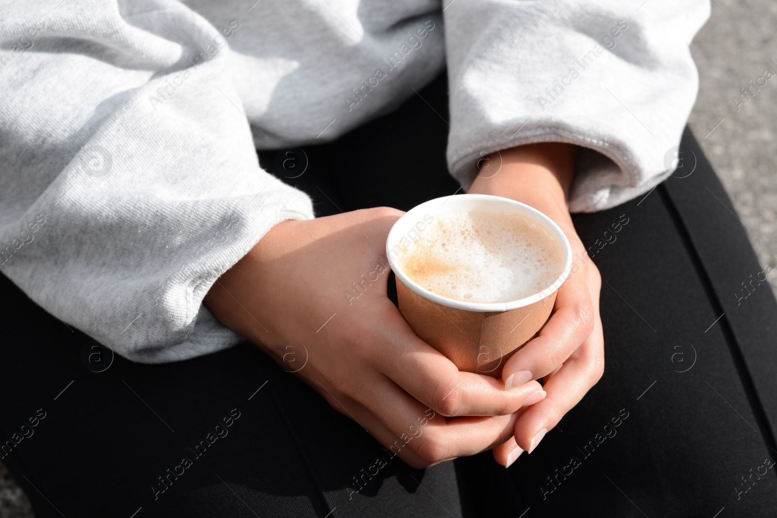 Photo of Woman sitting with cardboard cup of coffee, closeup