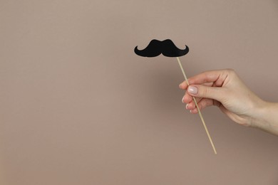 Photo of Woman with fake paper mustache on beige background, closeup. Space for text