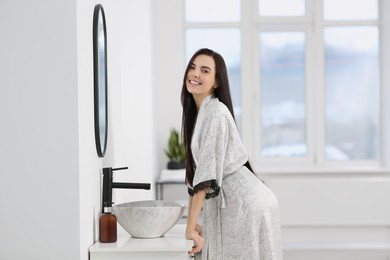 Photo of Beautiful happy woman wearing stylish bathrobe in bathroom