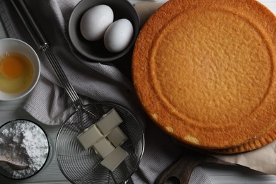 Photo of Delicious homemade sponge cake and ingredients on white wooden table, flat lay
