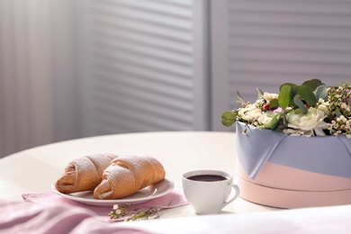 Plate with delicious croissants and cup of coffee on table