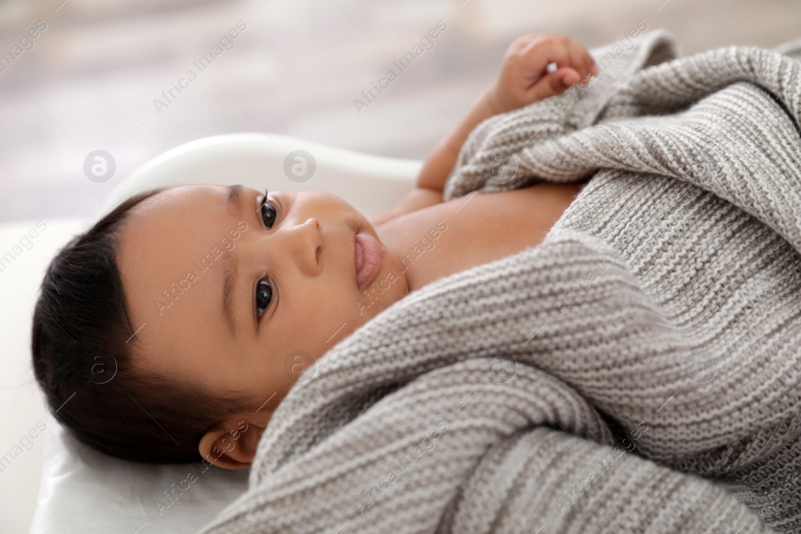 Photo of Cute African-American baby lying on scales indoors