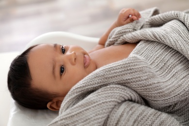 Cute African-American baby lying on scales indoors