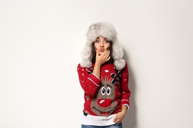 Photo of Young woman in Christmas sweater and hat on white background