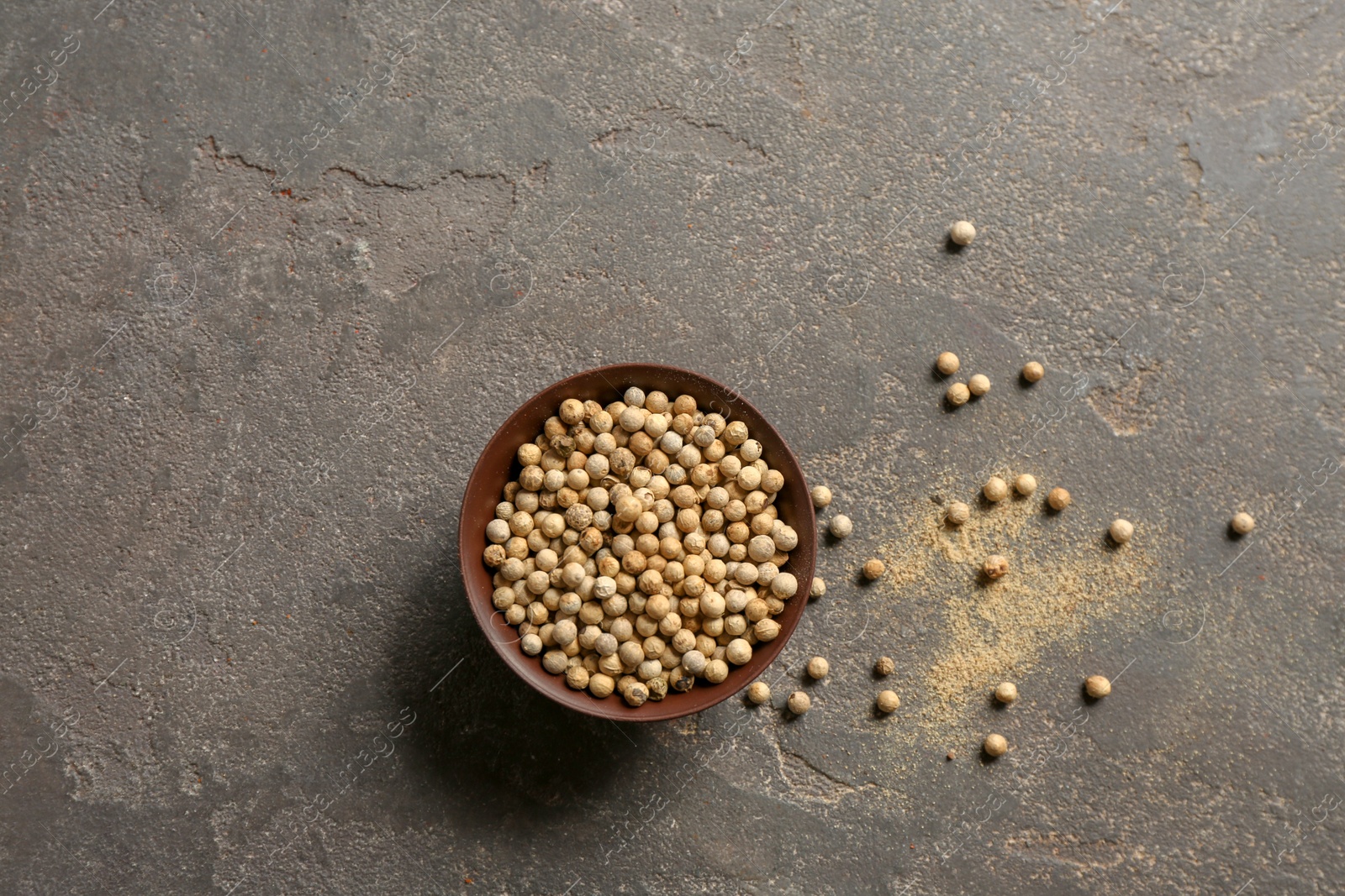 Photo of Bowl with white peppercorns on gray background, top view