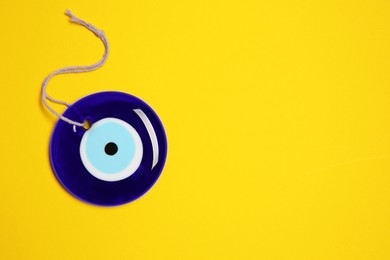 Evil eye amulet on orange background, top view. Space for text