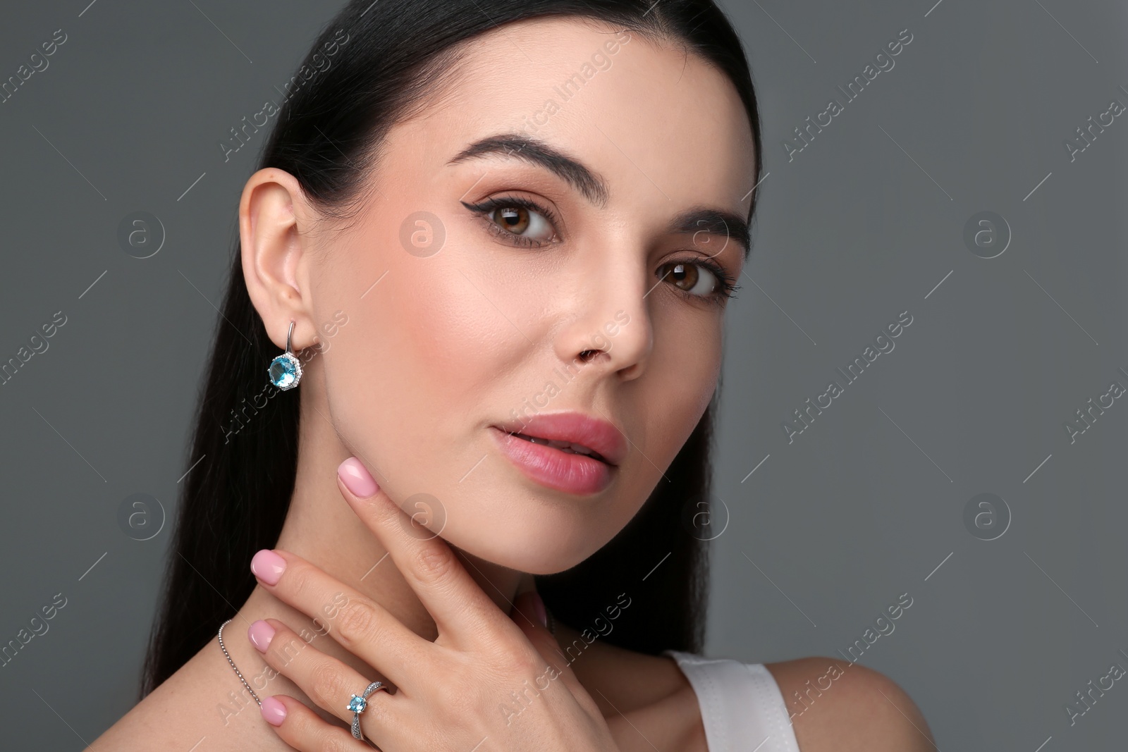 Photo of Beautiful young woman with elegant jewelry on dark grey background, closeup