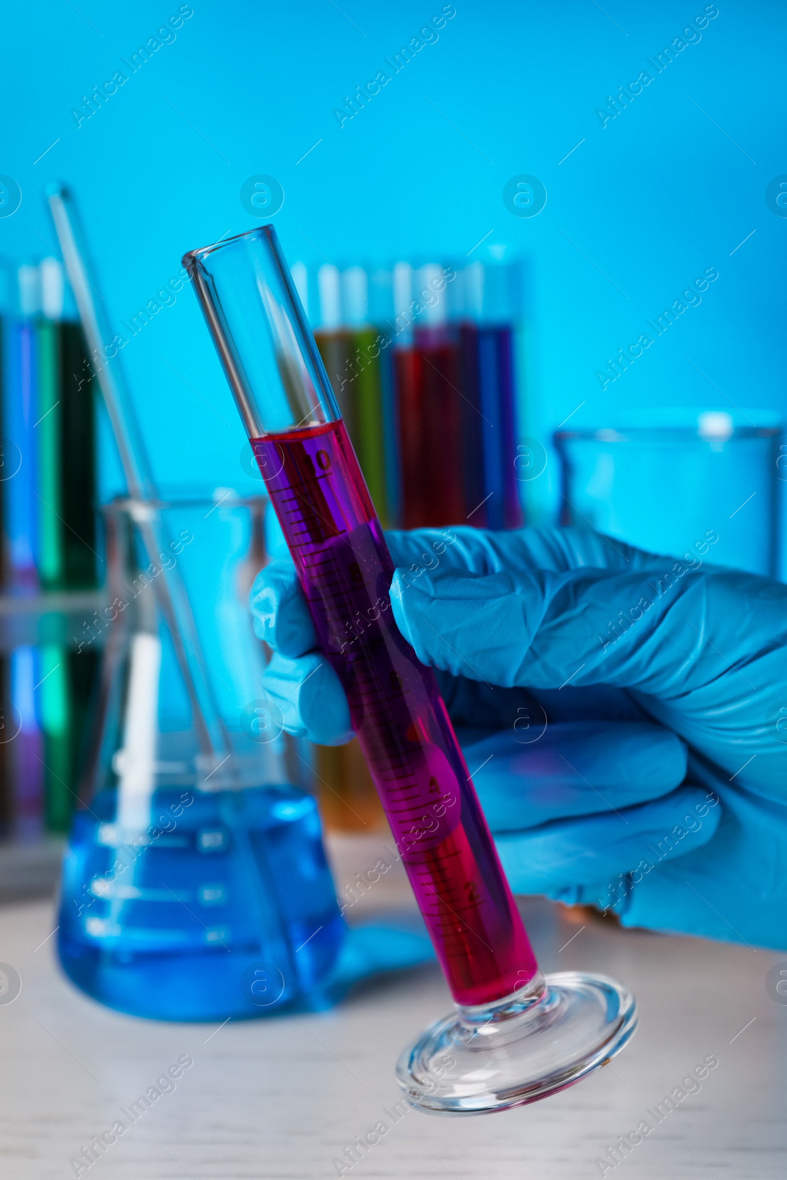 Photo of Scientist holding test tube with liquid at wooden table, closeup