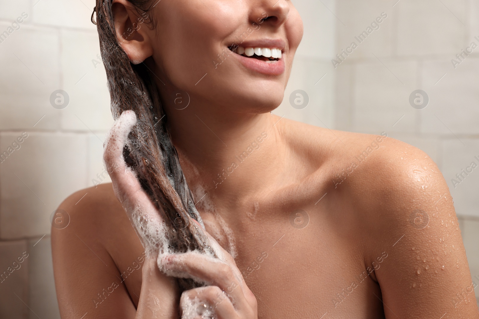 Photo of Happy woman washing hair while taking shower at home, closeup