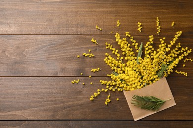 Photo of Beautiful mimosa flowers and envelope on wooden table, flat lay. Space for text