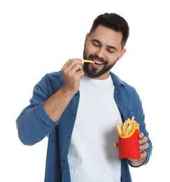 Young man eating French fries on white background