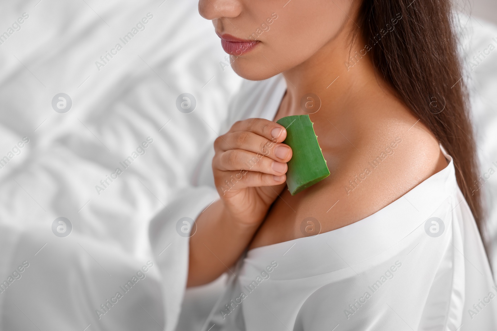 Photo of Young woman applying aloe gel from leaf onto her shoulder indoors, closeup. Space for text