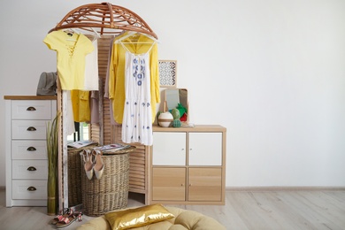 Photo of Stylish dressing room interior with wooden furniture and clothes