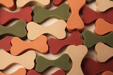 Photo of Many bone shaped vitamins for pets on beige background, closeup