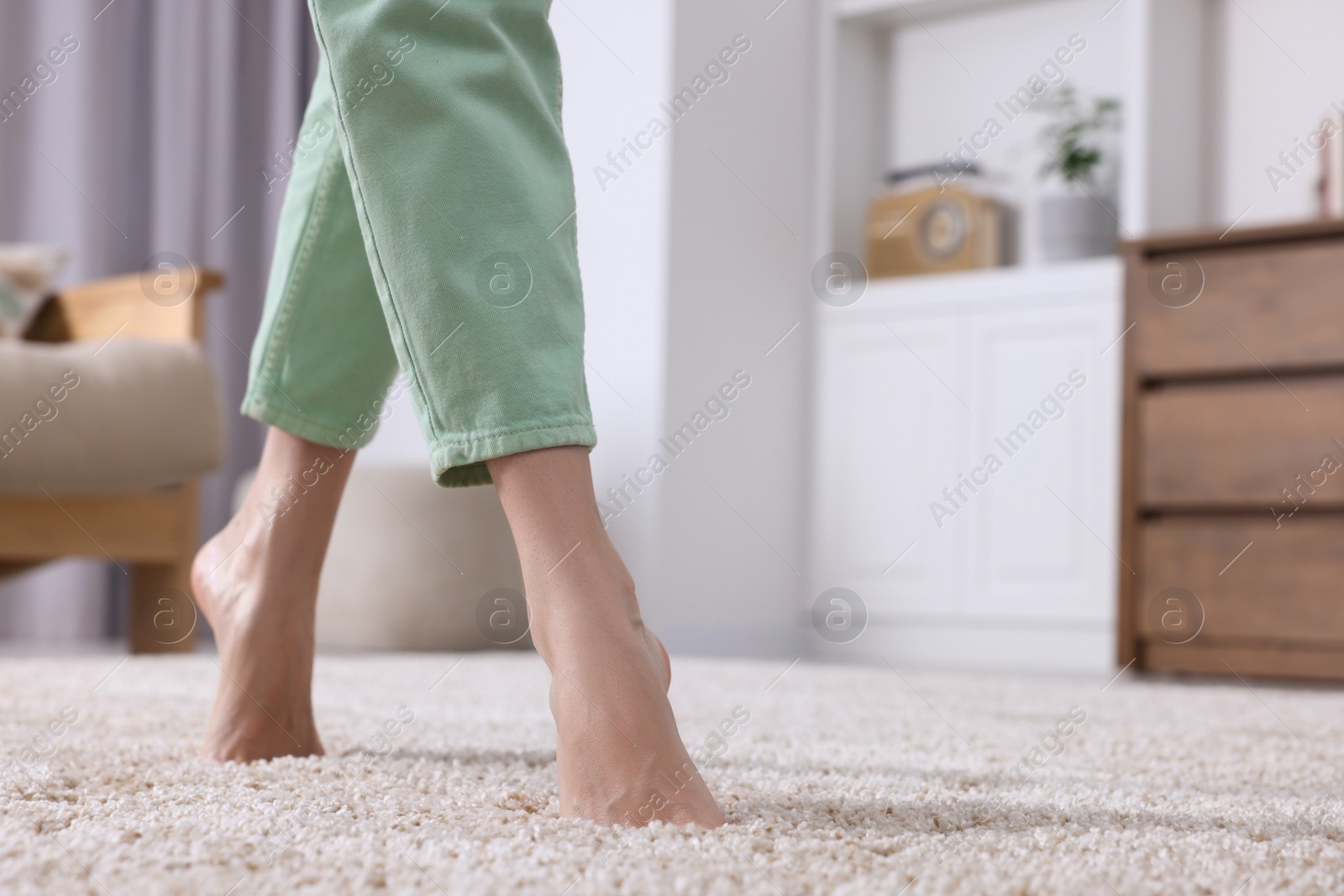 Photo of Woman walking on soft beige carpet at home, closeup. Space for text