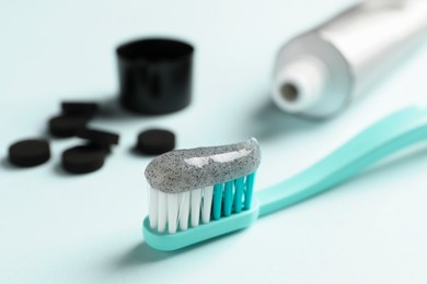 Photo of Brush with charcoal toothpaste on light background, closeup