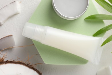 Lip balms, coconut and leaves on white background, flat lay