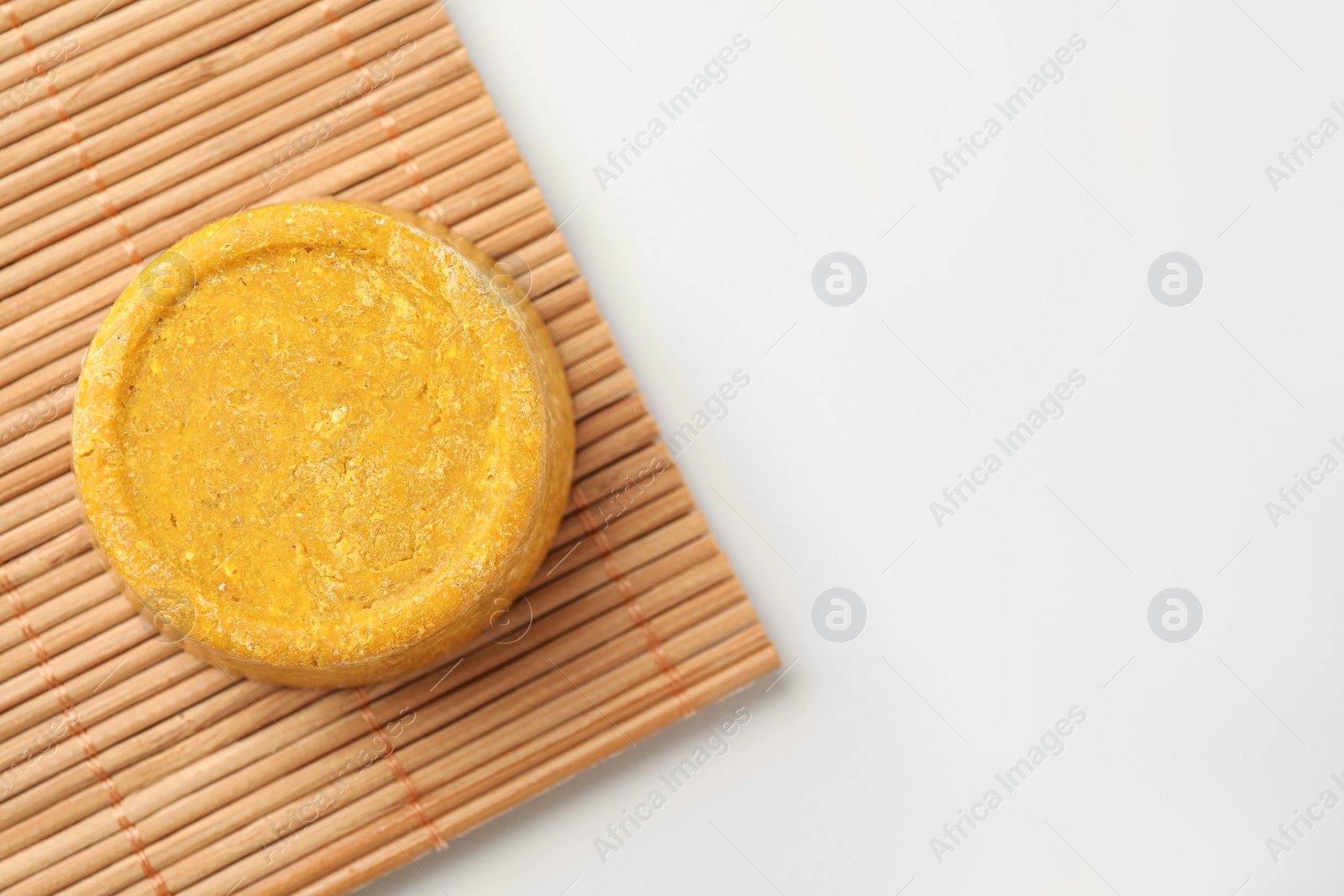 Photo of Yellow solid shampoo bar on light table, top view. Space for text