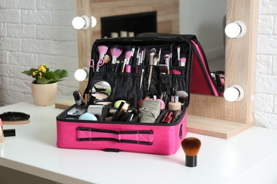 Photo of Beautician case with professional makeup products and tools on dressing table