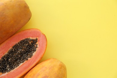 Photo of Fresh ripe cut and whole papaya fruits on light green background, flat lay. Space for text