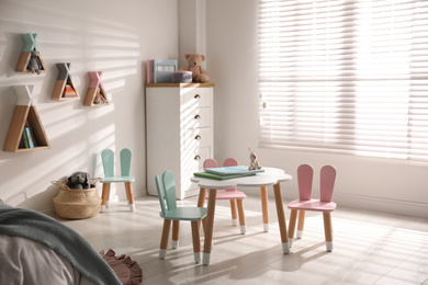 Small table and chairs with bunny ears in children's room interior