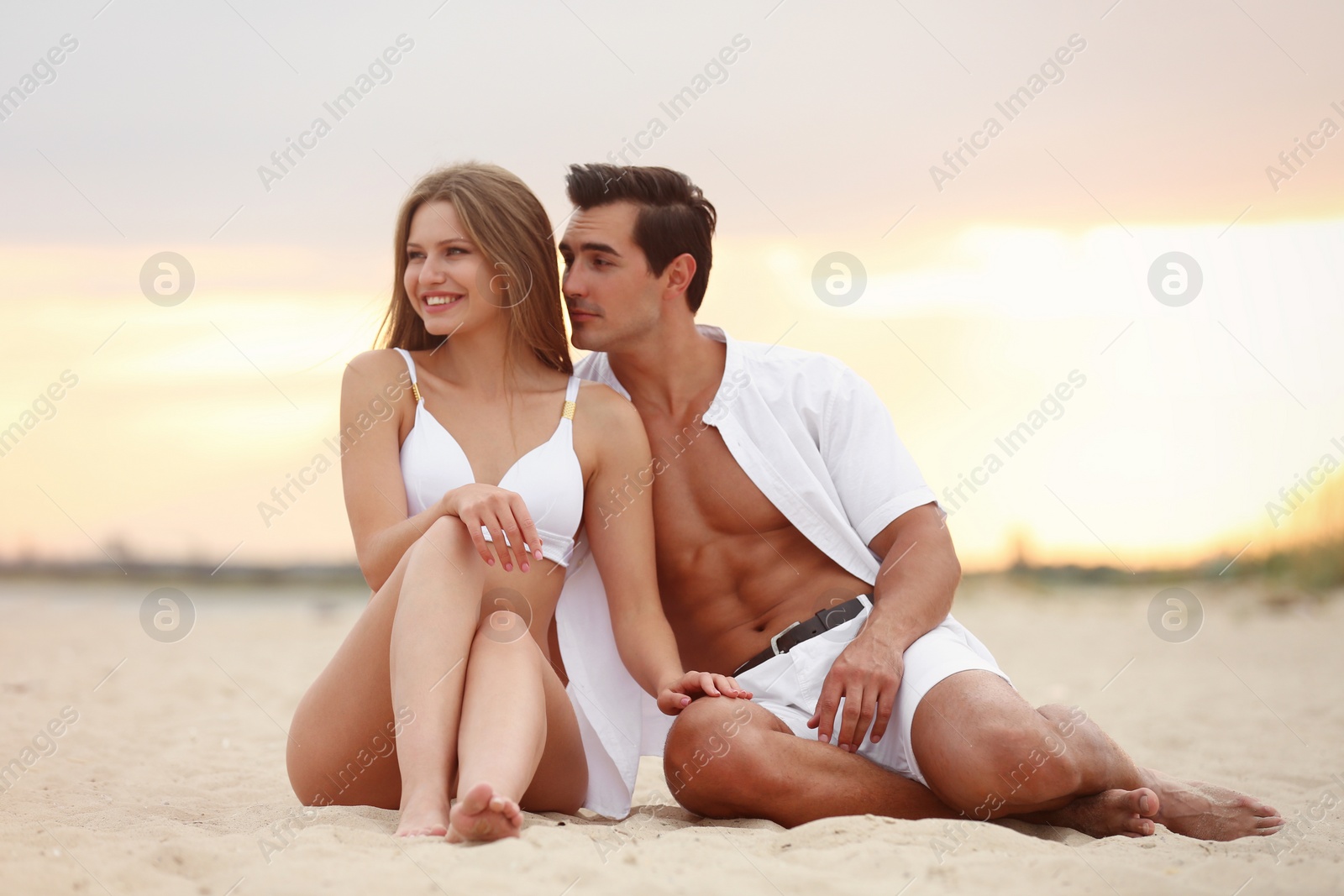 Photo of Happy young couple relaxing together on sea beach at sunset