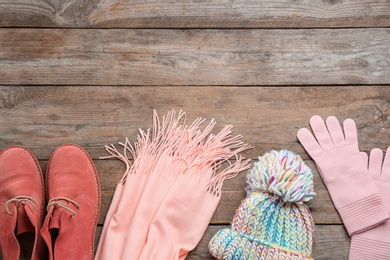 Flat lay composition with warm clothes on wooden background. Space for text